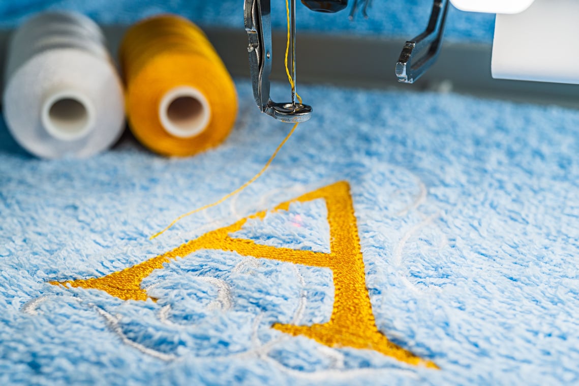 A alphabet design on towel in hoop of embroidery machine